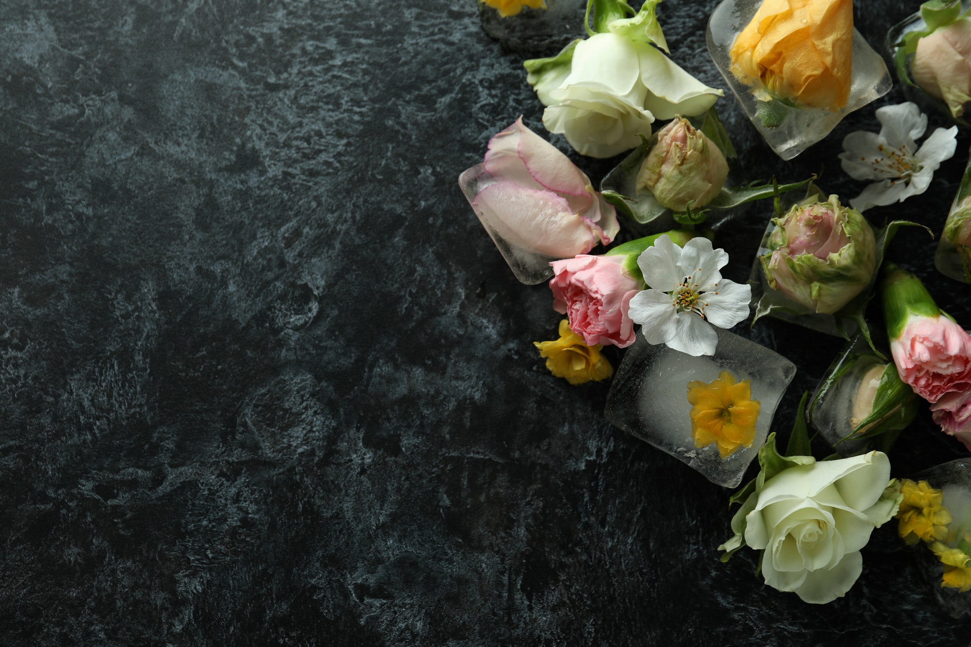 Flowers and ice cubes on black smokey background